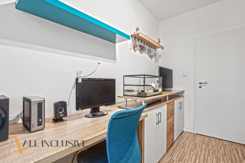 A desk with a computer and an aquarium, a floor with a wooden decor, a blue shelf.