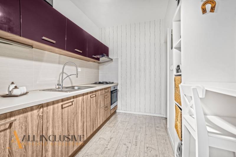 A kitchen with purple cabinets and a wood-patterned floor in a three-room apartment.