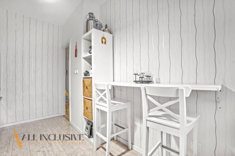 Dining area with a bar table and chairs, storage space, wooden decor flooring.