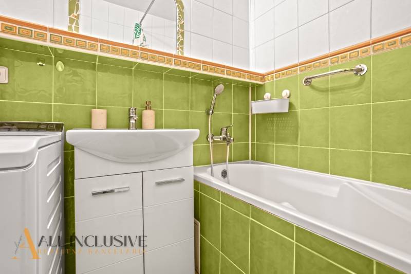 Bathroom with colorful tiles and a bathtub in a 3-room apartment, vibrant shades of green.