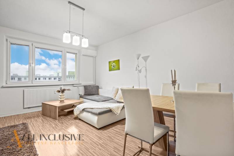 Living room in a three-room apartment with light-colored walls and a wooden decor floor.