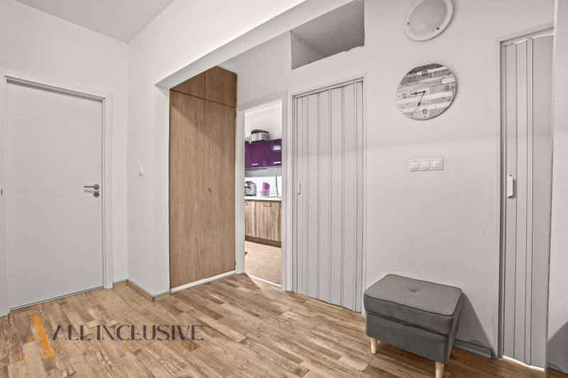 Interior of a 3-room apartment with a wooden decor floor, kitchen with purple cabinets.