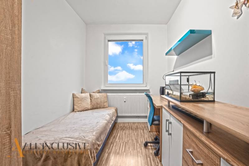 Children's room with a bed, desk, and aquarium in a 3-room apartment with a wooden decor floor.