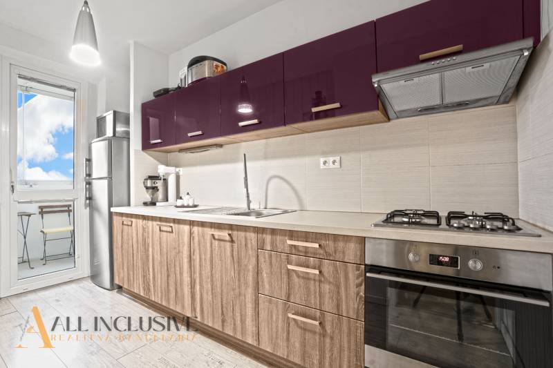 A kitchen in a 3-room apartment with purple cabinets and a wood-patterned floor.