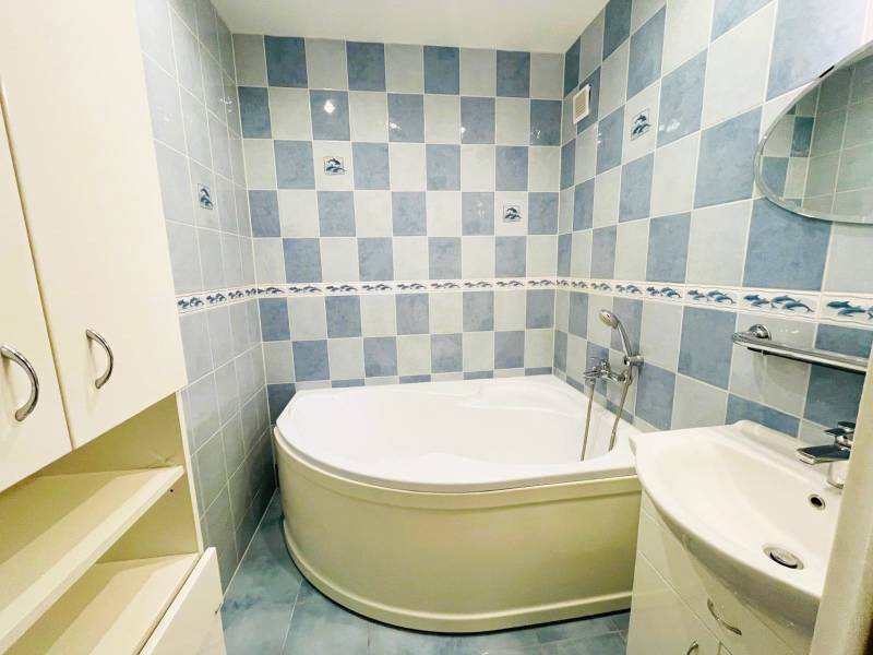 A bathroom with a built-in bathtub in a 3-room apartment with blue tiles and a sink.