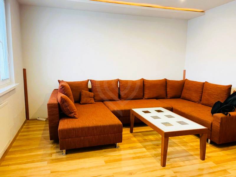 Living room with an orange sofa and a coffee table in a three-room apartment.