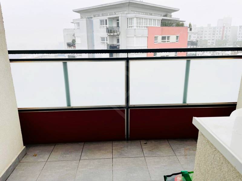 A balcony with milk-colored railings and a view of the surrounding buildings in Bratislava - Karlova Ves.