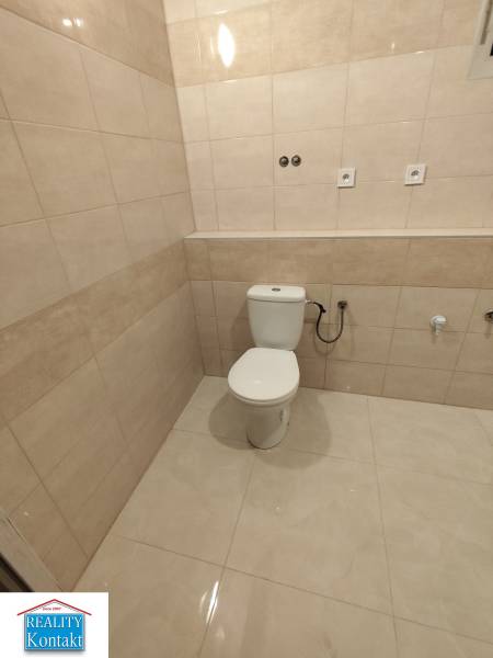 Bathroom in a 2-room apartment with a toilet and tiles with a beige decor.
