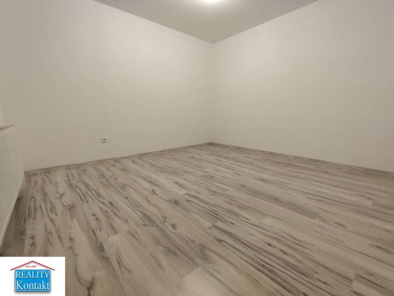 An empty room with wood-decor flooring in a 2-room apartment.