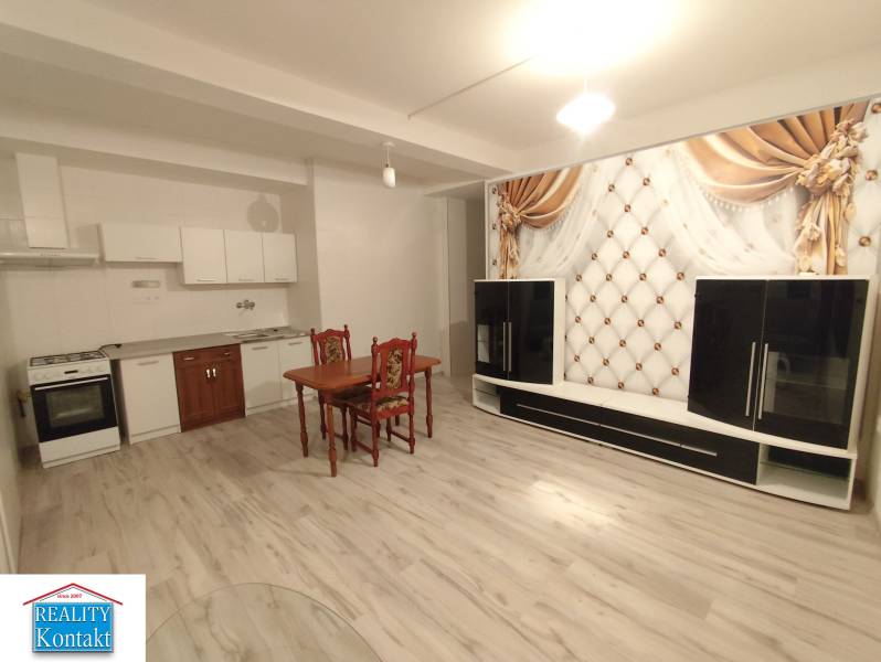Interior of a 2-room apartment with a kitchen, dining table, and floor with wood decor.