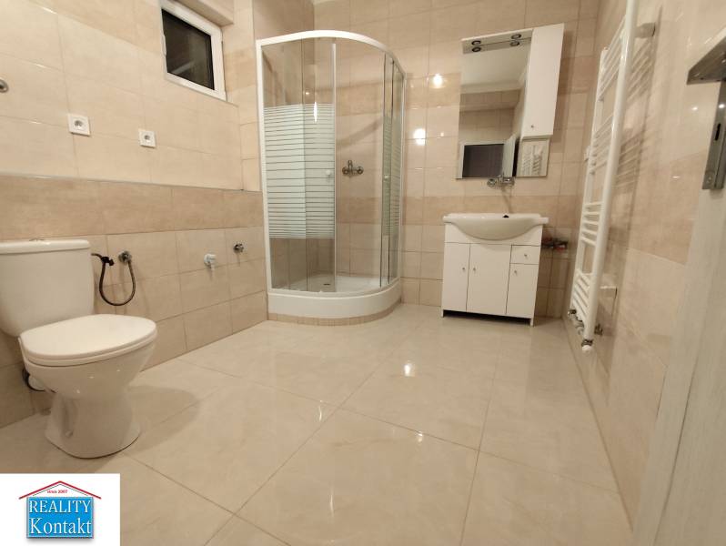 Spacious bathroom with a toilet, shower, and sink in a 2-room apartment.