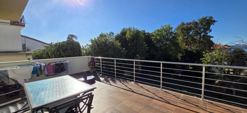 A terrace overlooking the trees and drying laundry in a 3-room apartment in Crikvenica.