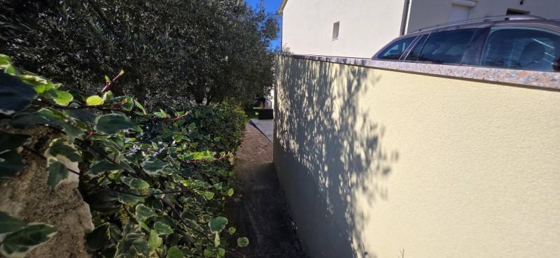 A narrow alley between the house and greenery in Crikvenica, suitable for pleasant walks.