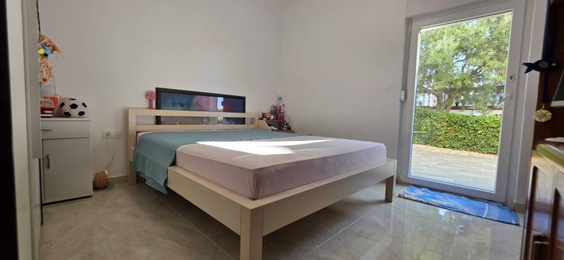 A bedroom with a bed and access to the garden in a 3-room apartment.