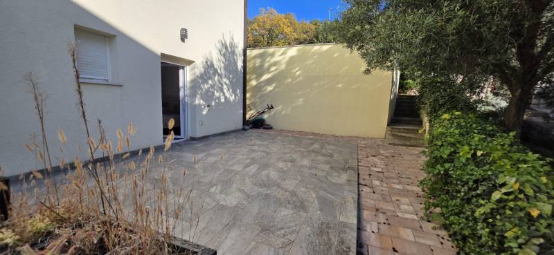 A garden with a 3-room apartment in Crikvenica with a paved terrace and greenery.