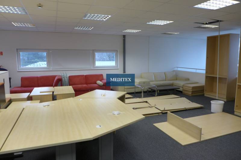 A commercial space with sofas, tables, and disassembled furniture on a dark floor.
