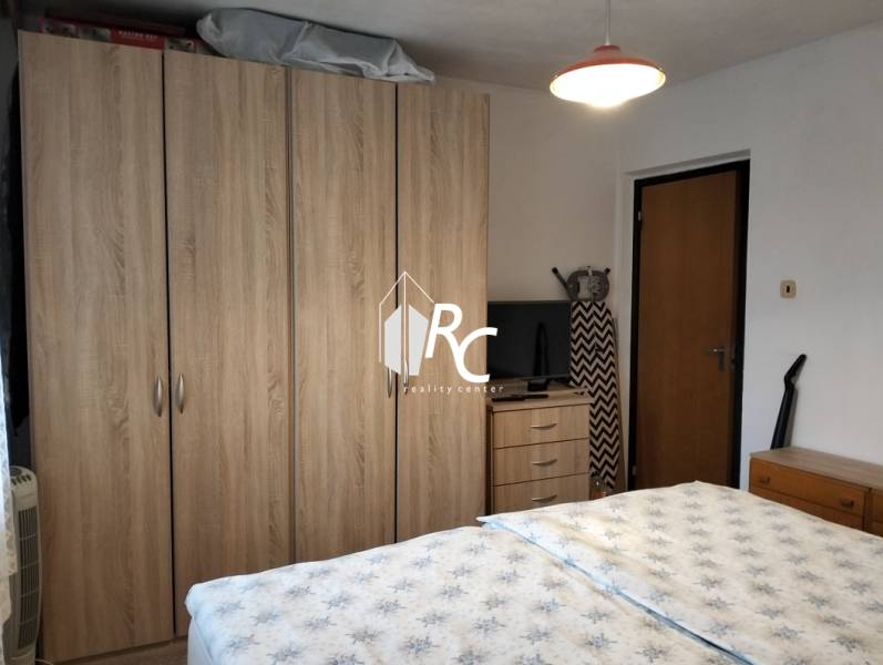 A bedroom with dark furniture, a television, and a bed, typical for a 3-room apartment.