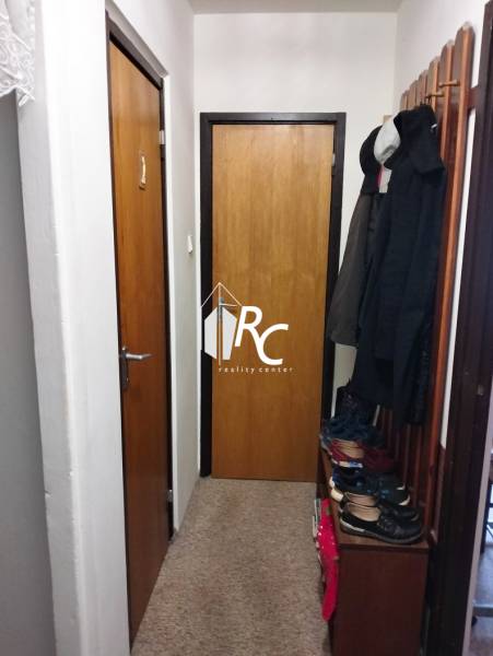 A narrow hallway with a shoe rack and a coat rack in a three-room apartment.