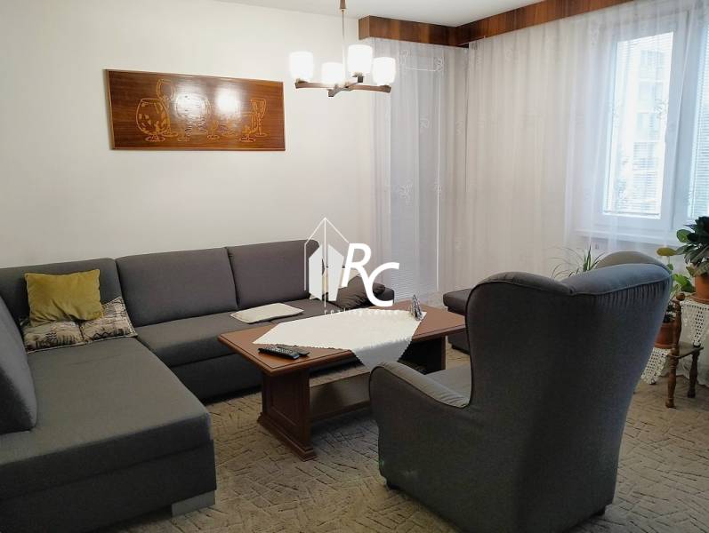 Living room in a three-room apartment with a sofa, an armchair, and a table.