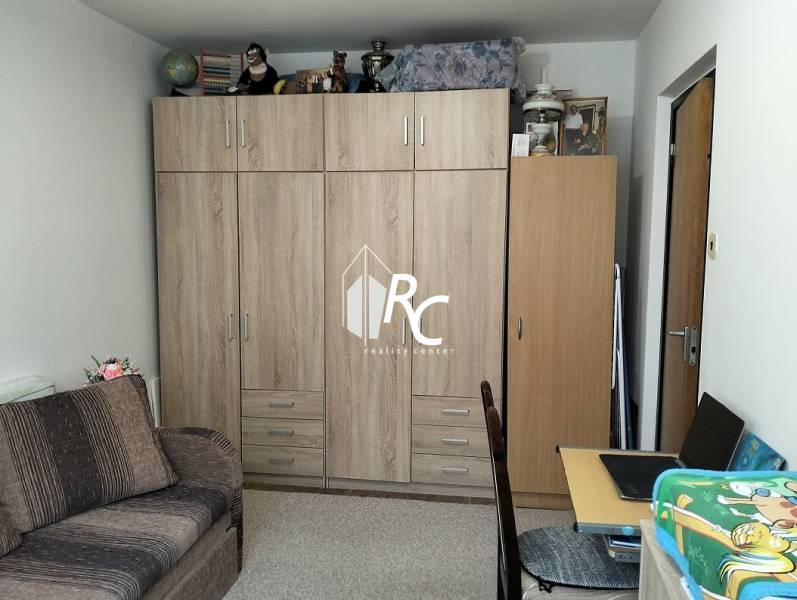 A room in a 3-room apartment with furniture featuring a wooden decor and a sofa.