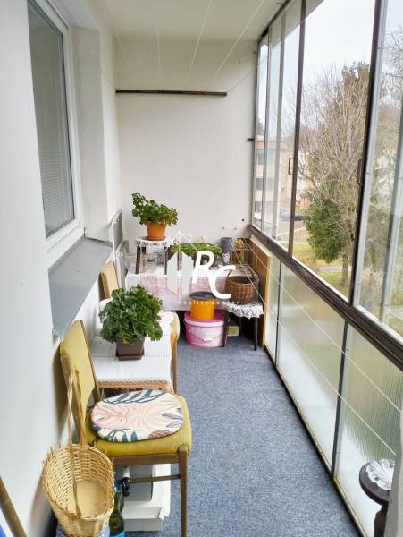 A glazed balcony with flowers and a chair, 3-room apartment.