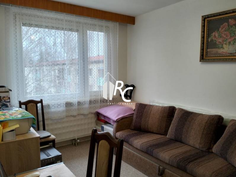 Living room in a 3-room apartment with a sofa, wooden decor furniture, lace curtains.