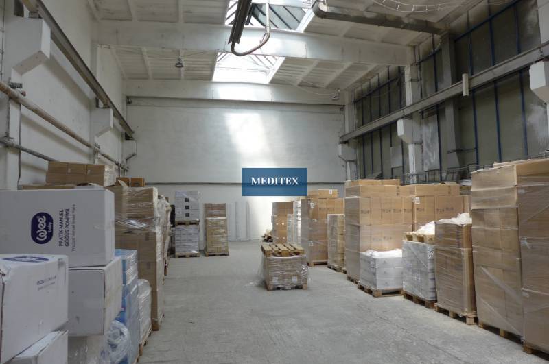 In the warehouse, pallets with cartons and crates are arranged on a concrete floor.