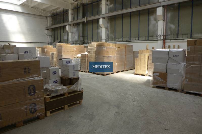In the warehouse hall, there are pallets with cardboard boxes and packages of the Meditex brand.