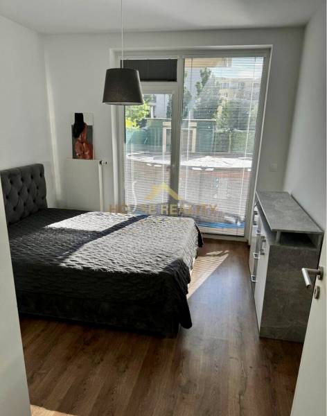 Bedroom in a 3-room apartment with a bed, window with blinds, and flooring with a wooden decor.