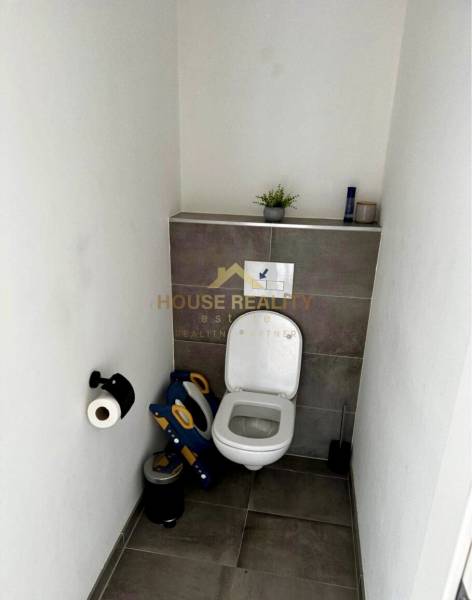 A toilet with decorative tiles and a child seat in a 3-room apartment.