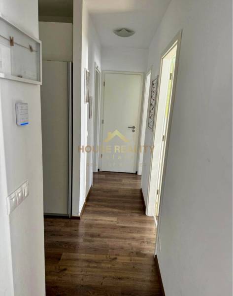 A hallway in a 3-room apartment with a wooden decor floor and white walls.