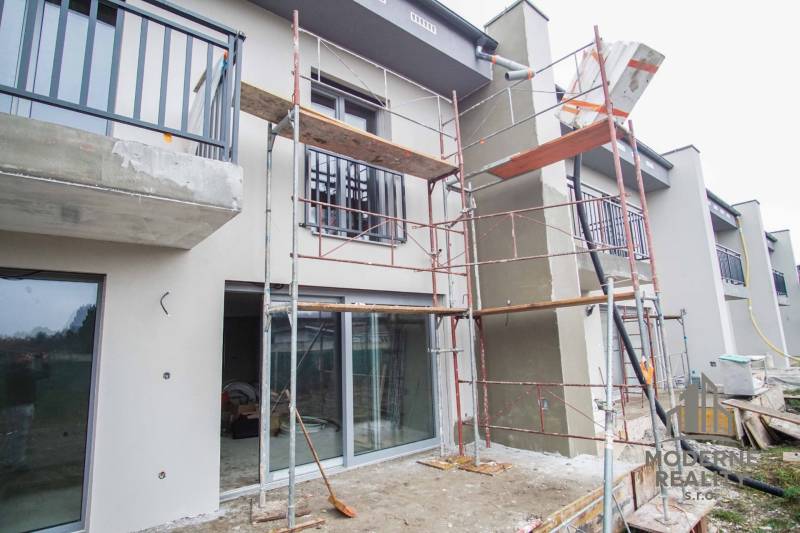 Unfinished facade of a family house in Nové Zámky, scaffolding, large windows, and balconies.