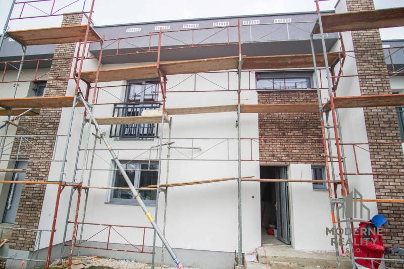 A family house in Nové Zámky with scaffolding and brick cladding during facade renovation.