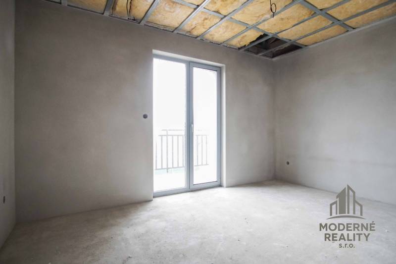 Empty room with a large window and an unfinished ceiling in a family house.
