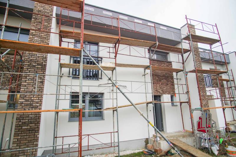 A family house in Nové Zámky during renovation with scaffolding and brick detail on the facade.