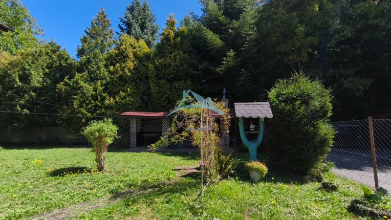 A garden with a gazebo near a cottage in Dolné Strháre, surrounded by dense trees and lawn.