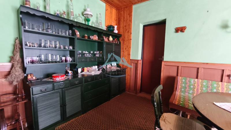 A cottage with a rustic interior, green cabinet, glass cups, wooden decor, carpet.