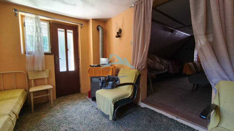The interior of a cabin with wooden doors, a spiral stove, and comfortable armchairs.