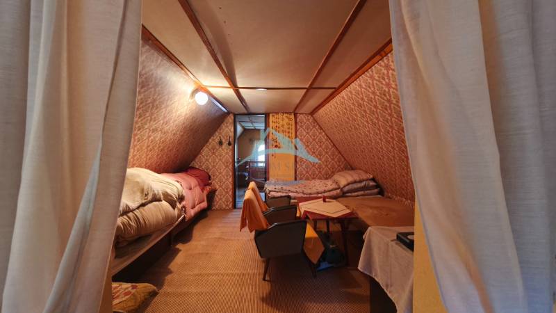 Interior of a cabin with a wood-patterned floor, beds, and chairs.