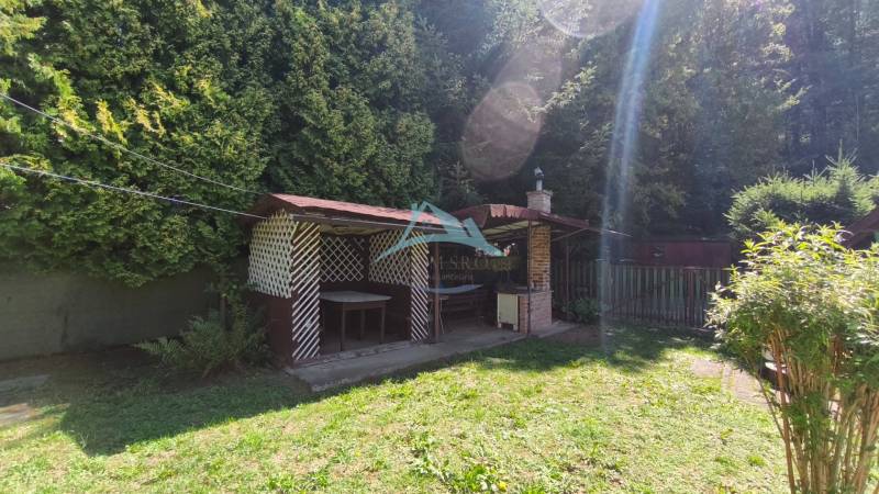 A garden at the cottage in Dolné Strháre with a gazebo, lawn, and surrounded by trees.