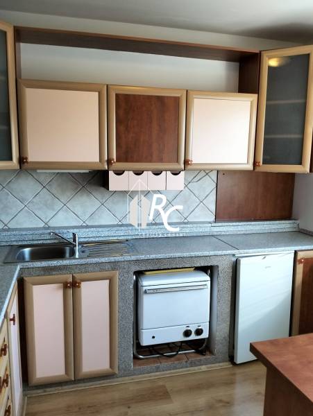 The kitchen of a one-room apartment with a wooden decor floor and a kitchen counter.