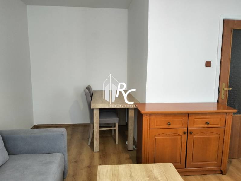 Interior of a 1-room apartment with a sofa, table, and floor with a wood decor.