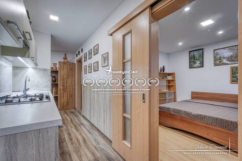 Kitchen corner with a cooktop and a bed, 3-room apartment with a wooden decor floor.