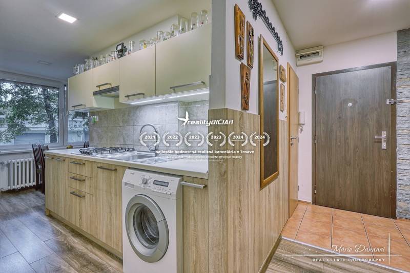 A kitchen in a 3-room apartment with a wood-patterned floor and built-in appliances.