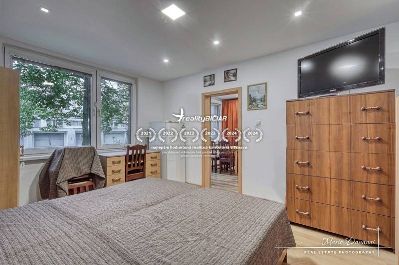 Bedroom in a 3-room apartment with a bed, drawers, and a TV on the wall.