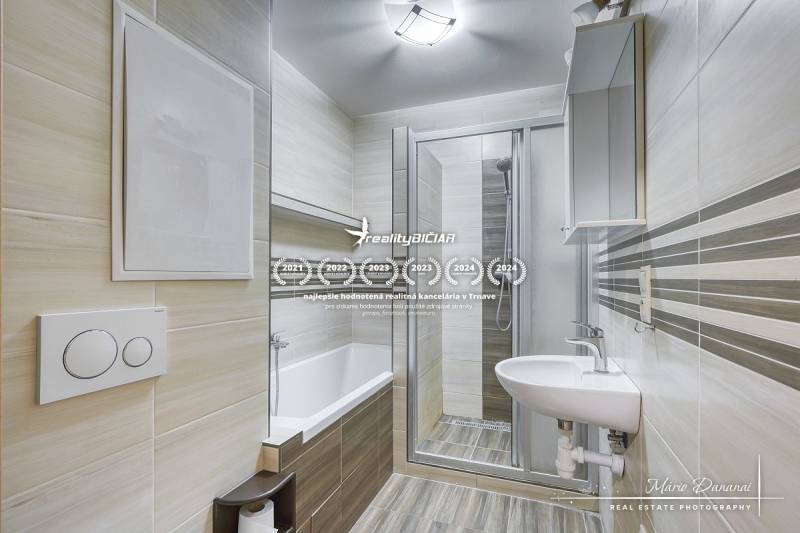 Bathroom in a 3-room apartment with a bathtub, shower corner, and floor with a wooden decor.