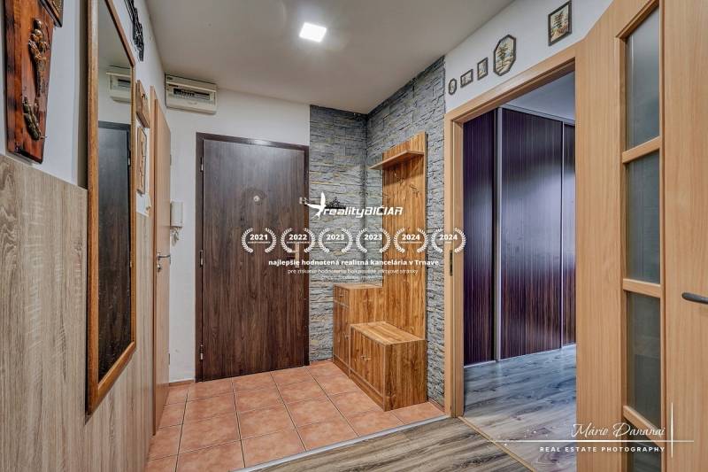 The entrance hall of a three-room apartment with ceramic tiles and a floor with a wooden decor.