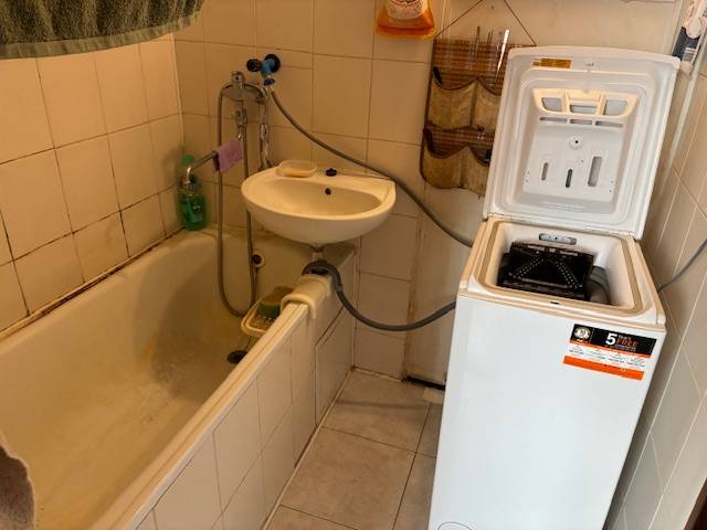 A bathroom in a 3-room apartment with a bathtub, sink, and washing machine in a compact layout.