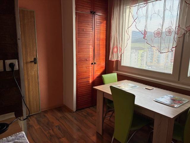 Dining area in a 3-room apartment, wooden decor flooring, green chairs, cabinets.