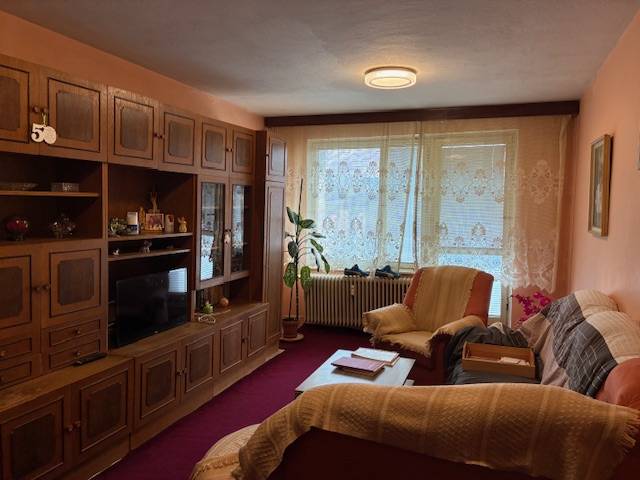 Living room in a 3-room apartment with rustic furnishings, carpets, and curtains.